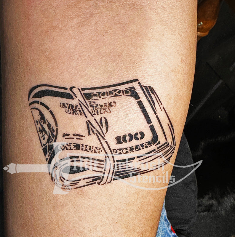 Tattoo of folded $100 bills airbrushed on a person's arm created with a stencil from Hilt Airbrush Stencils..