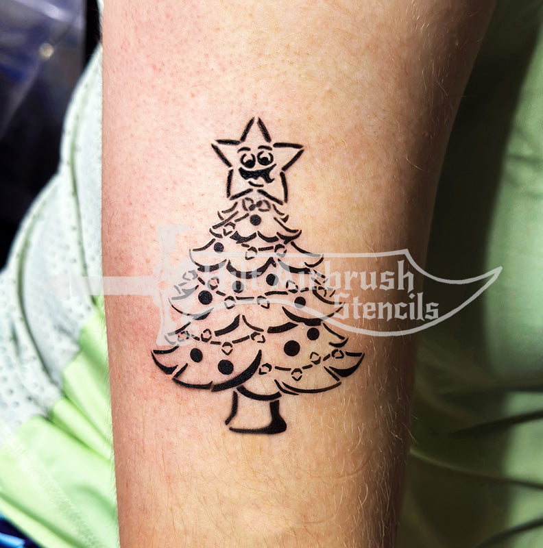 Airbrush tattoo of a Christmas tree design on a person's arm, created with a Hilt Airbrush Stencil