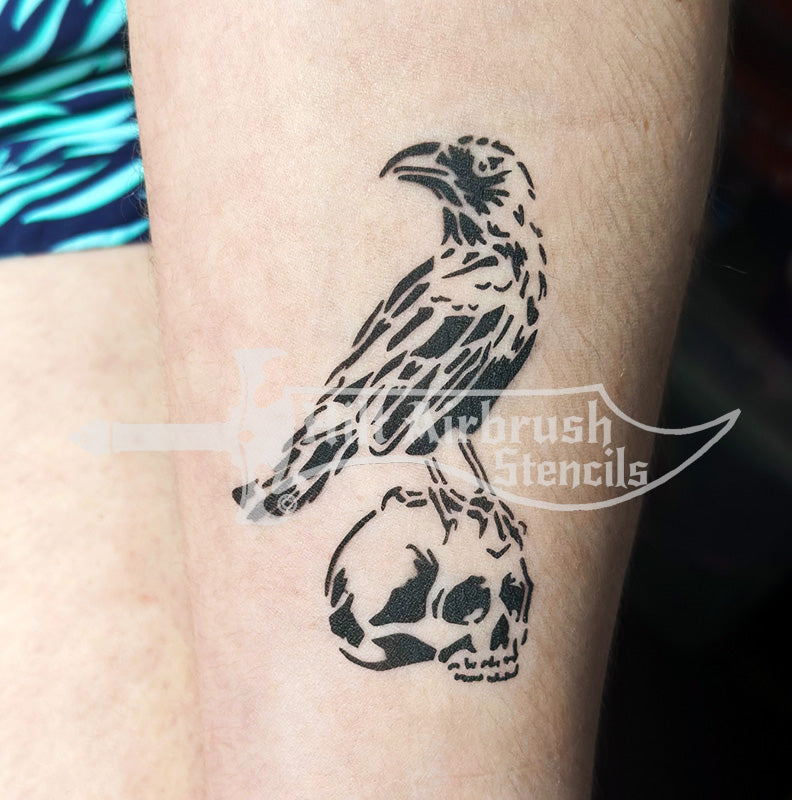 Tattoo design of a raven and skull on someone's arm created with a Hilt Airbrush Stencil