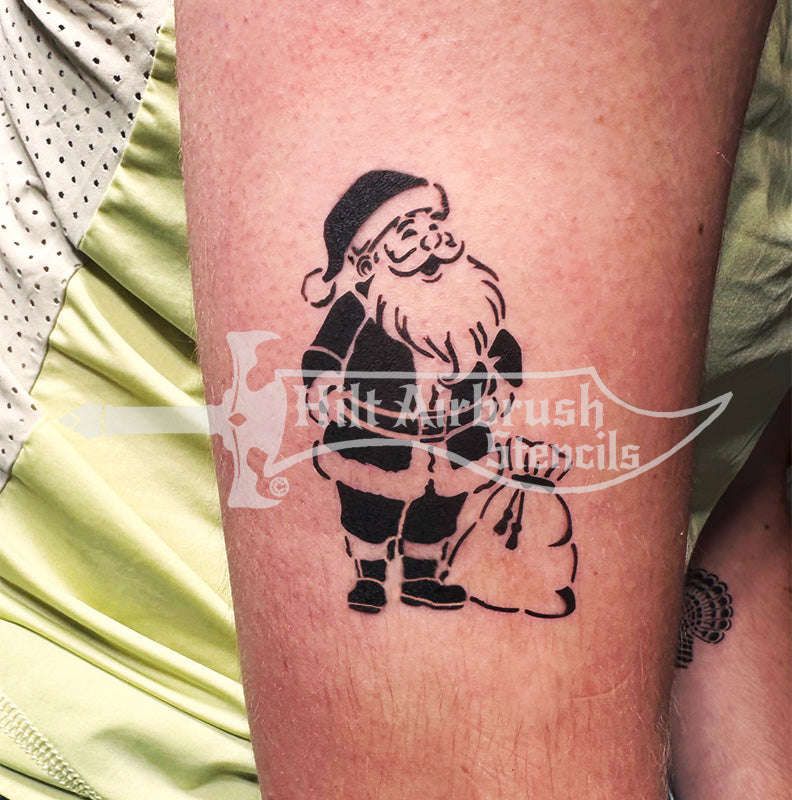 A Christmas tattoo of Santa Claus airbrushed on a person's arm, created with a Hilt Airbrush tattoo stencil