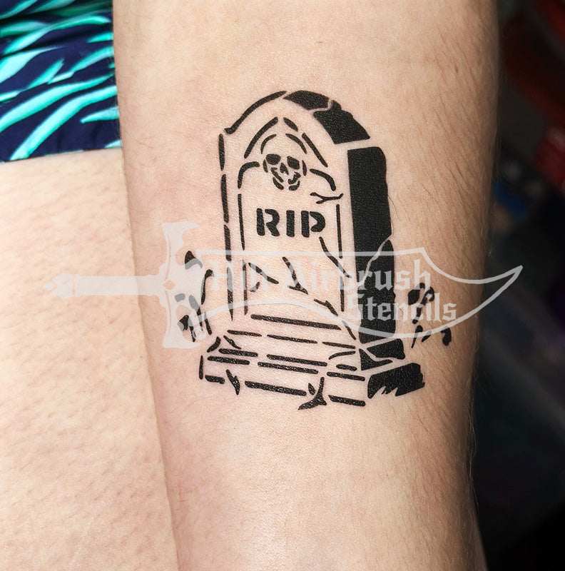 Black tattoo of a tombstone with 'RIP' on a person's arm created with airbrush stencil