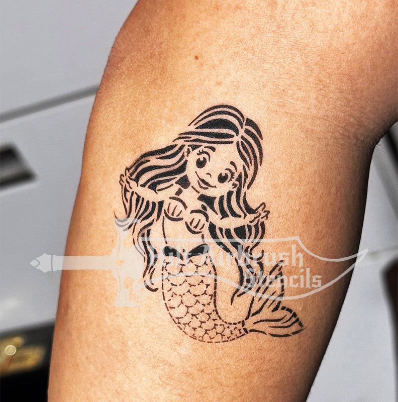 Mermaid tattoo airbrushed on a person's arm with a stencil, perfect for children's party designs.