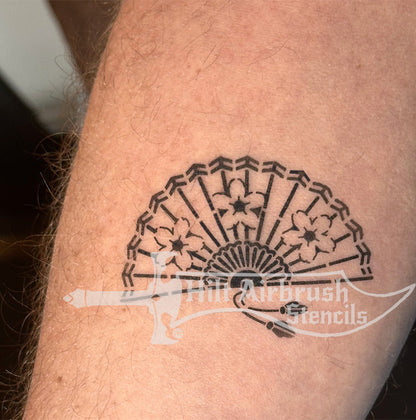 Airbrush tattoo of a decorative Chinese fan design sprayed on a person's arm with a stencil from Hilt Airbrush Stencils.