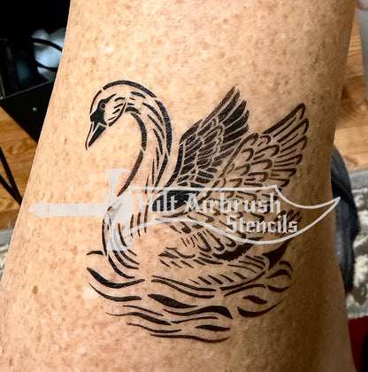 A black temporary airbrush tattoo of a swan with wings spread, applied to human skin. 