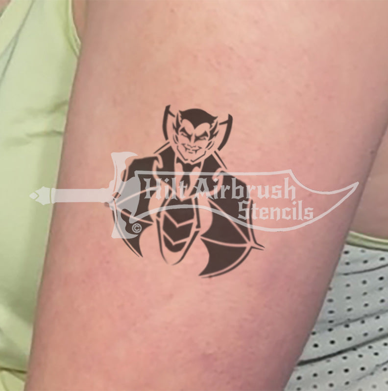 Black airbrush tattoo of a grinning vampire on a person's arm, created with a Hilt Airbrush stencil