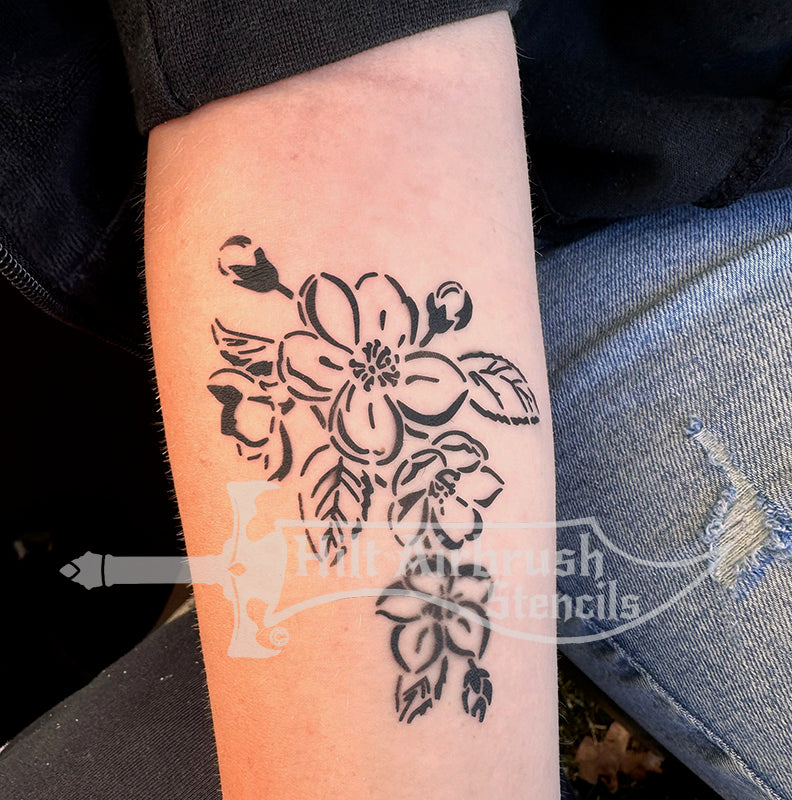 Airbrush tattoo of a floral apple blossom design sprayed on a person's arm from Hilt Airbrush Stencils.