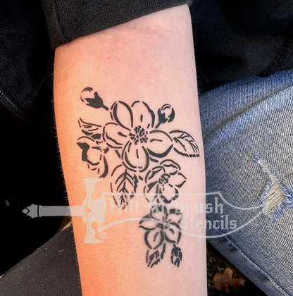 Airbrush tattoo of a floral apple blossom design sprayed on a person's arm from Hilt Airbrush Stencils.