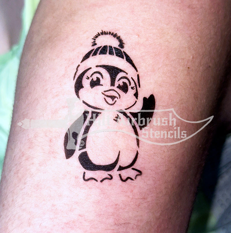 Airbrush tattoo of an adorable penguin design on someone's arm created with a Hilt Airbrush Stencil