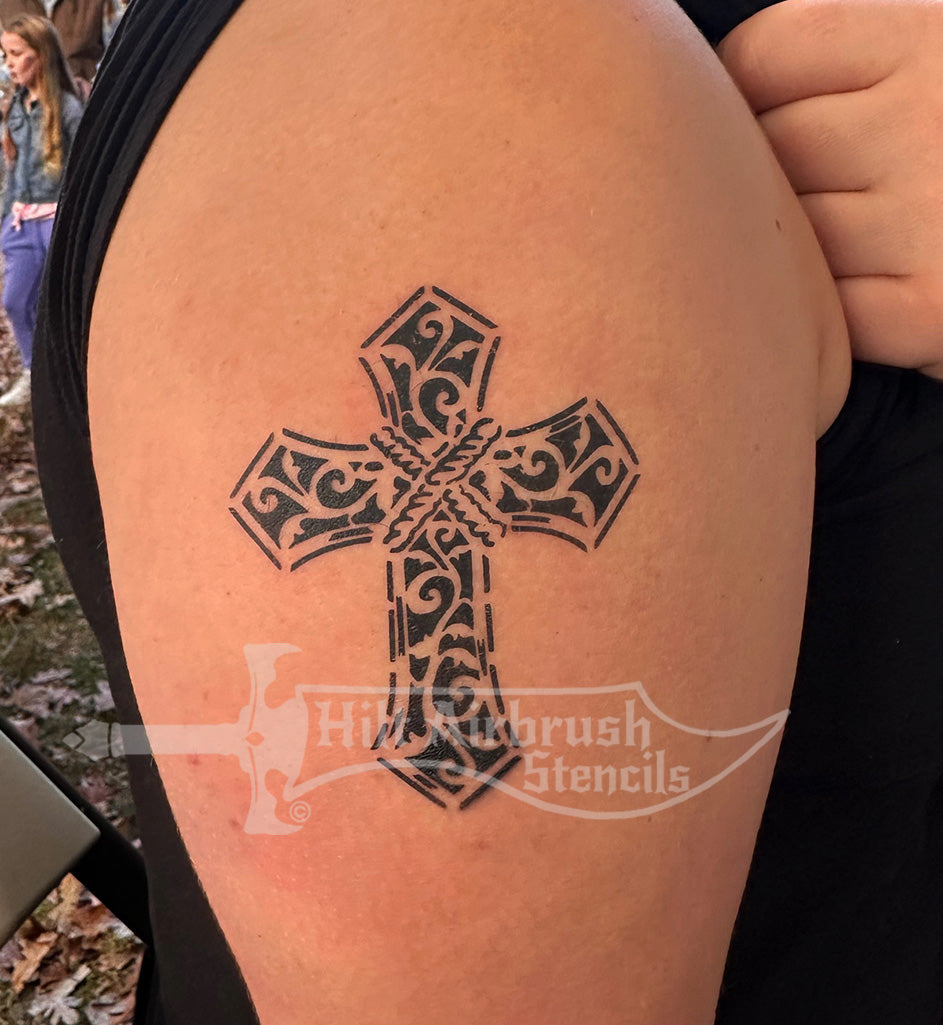 Tattoo of a classic cross design airbrushed on a person's arm, created with a stencil from Hilt Airbrush Tattoos.