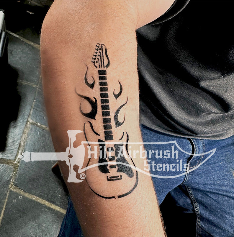 Tattoo of an electric guitar with flames airbrushed on a person's arm created by Hilt Airbrush Stencils.