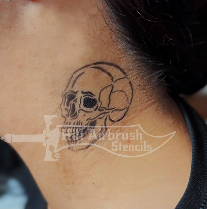 A human skull tattoo airbrushed on someone's neck using a stencil from Hilt Airbrush Stencils.