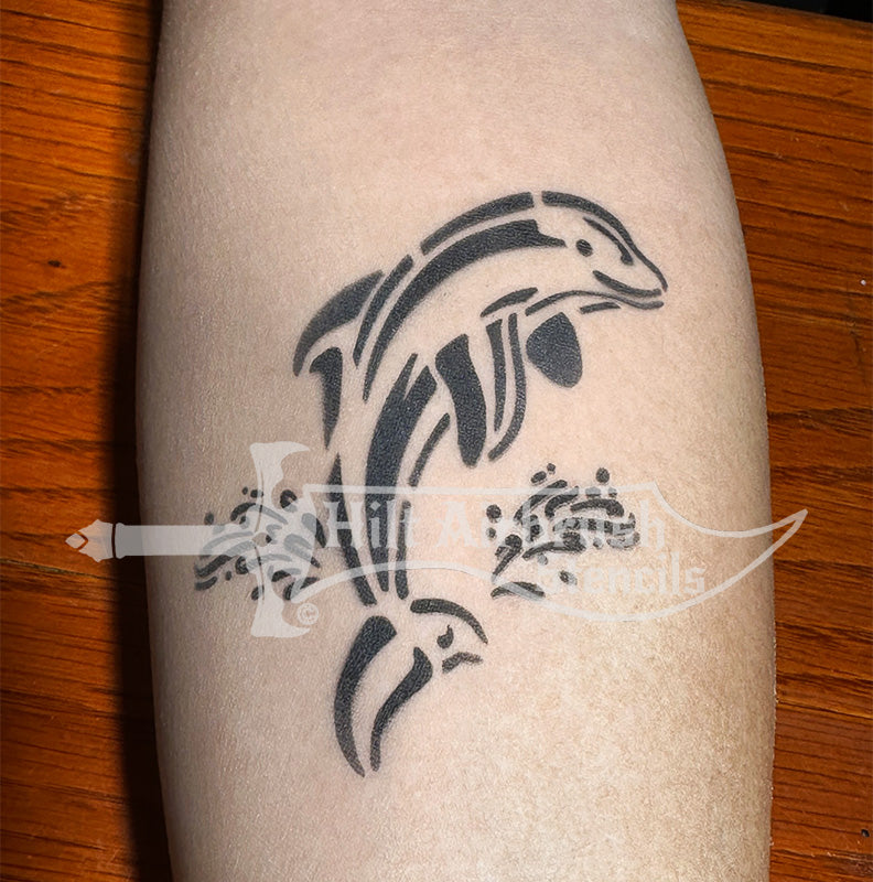 Airbrush tattoo of a stylized dolphin sprayed on a person's arm using a stencil designed by Hilt Airbrush Stencils.