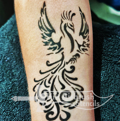 Black tribal style phoenix tattoo on a person's arm designed by Hilt Airbrush Stencils.