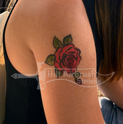 Red rose tattoo airbrushed on a person's arm with 'Hilt Airbrush Stencils' branding.