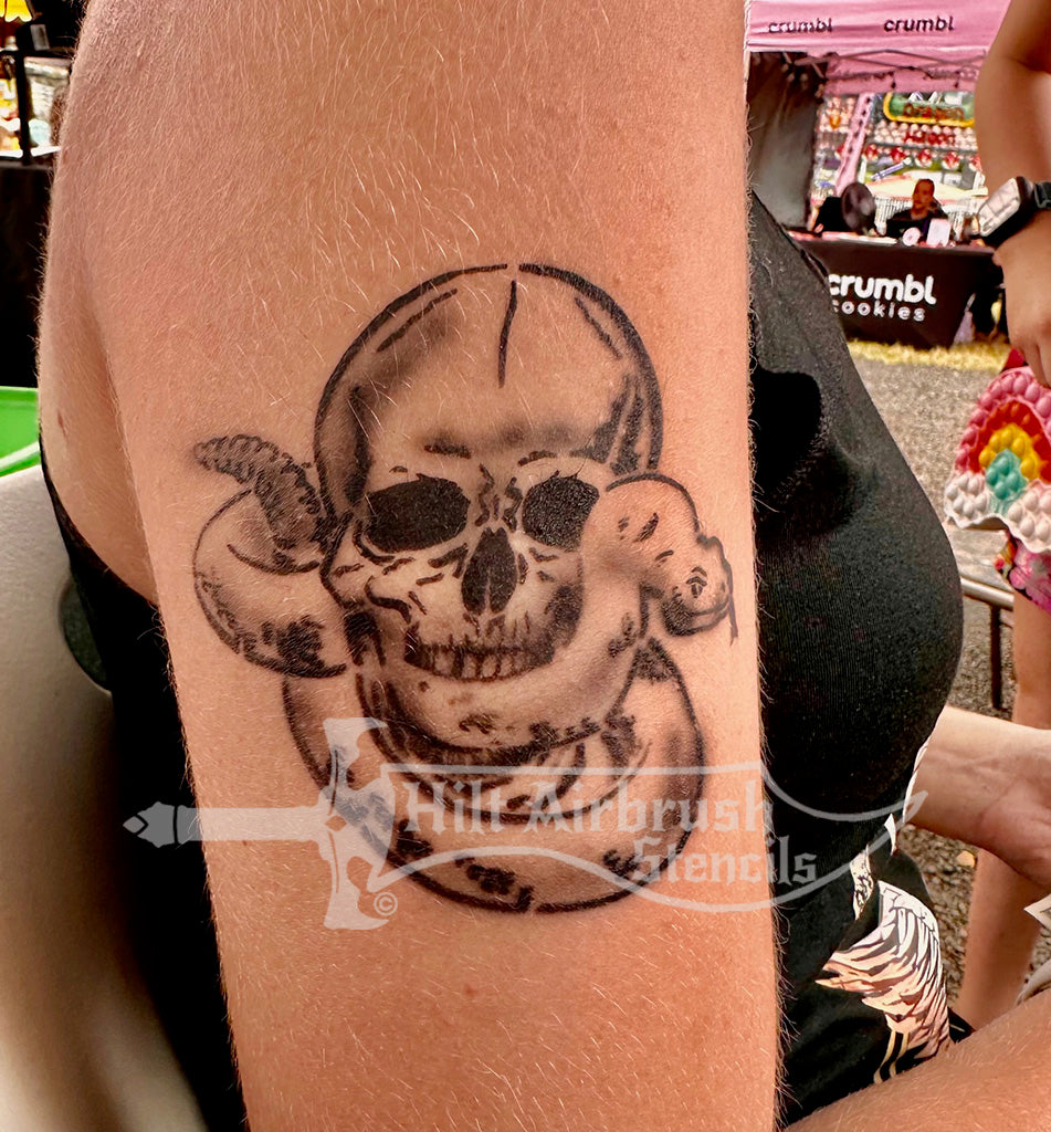 Skull with a snake tattooed on a person's arm, created with a Hilt Airbrush stencil.