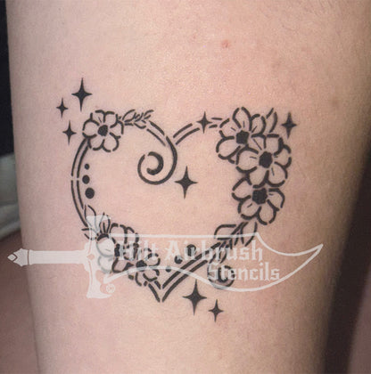 Heart-shaped tattoo with floral designs airbrushed on a person's arm, created with a Hilt Airbrush Stencil.